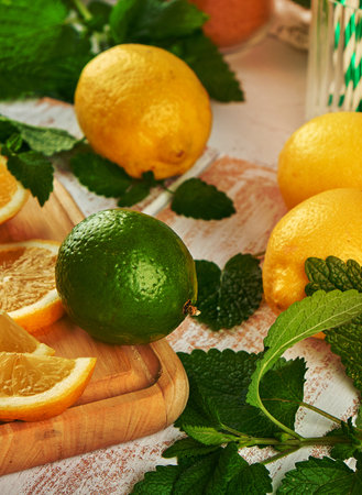 ripe yellow lemons and lime, mint green on a white wooden board, ingredients for lemonade or mojitoの写真素材