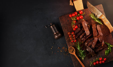 roasted piece of beef ribeye cut into pieces on a vintage brown chopping board. Delicious steak, copy spaceの写真素材