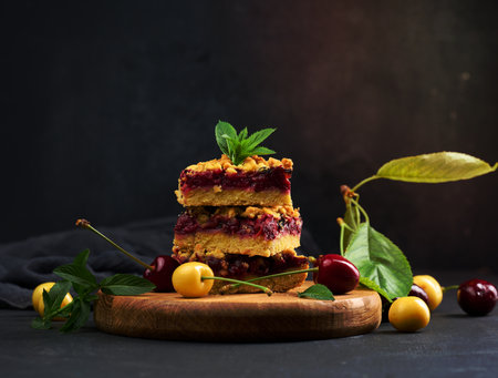Square slices of cherry crumble lie in a stack on a black board, summer dessertの写真素材