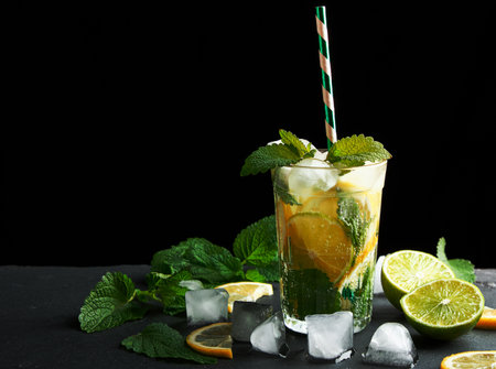 summer refreshing drink lemonade with lemons, mint leaves, ice cubes and lime in a glass on a black background,  copy spaceの写真素材