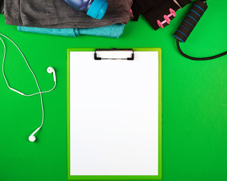 sports women's clothing for fitness, top view, green background, in the middle of the holder for the paper with empty white sheetsの写真素材