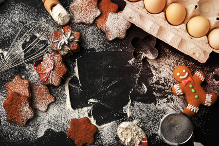 Star shaped baked gingerbread cookies sprinkled with powdered sugar on a black table, top viewの写真素材