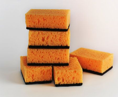 stack of yellow kitchen sponges for washing dishes on a white backgroundの写真素材