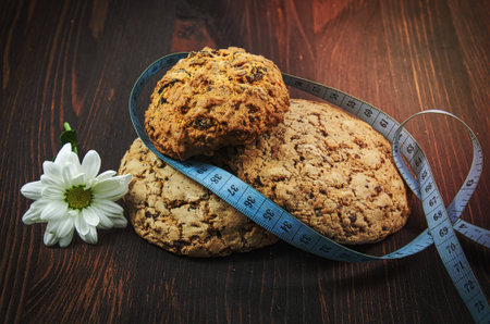 Three dietary biscuits and homemade cakes and meter on brown wooden surfaceの写真素材