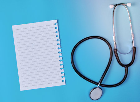 white piece of paper in a line and a medical stethoscope on a blue backgroundの写真素材