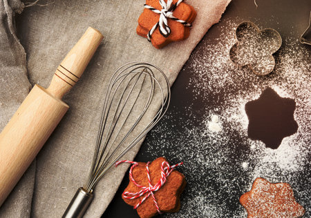 Star shaped baked gingerbread cookies sprinkled with powdered sugar on a black table, top viewの写真素材