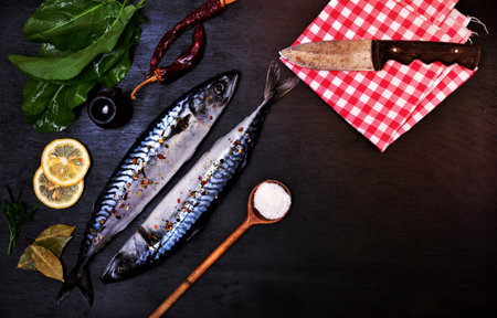 Two fresh whole mackerels in spices on a black backgroundの写真素材