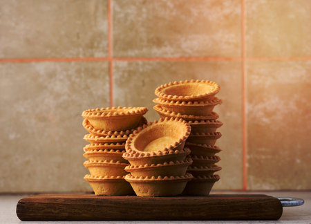 Stack of empty baked round canape baskets on a wooden board, round empty tartletsの写真素材