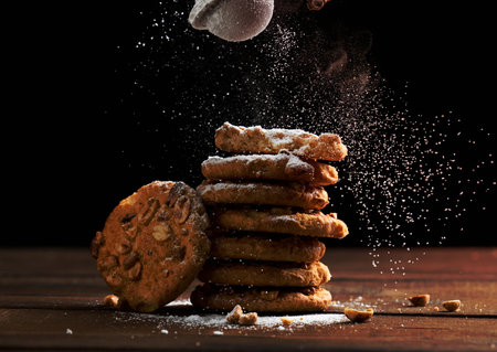 stack of baked round cookies sprinkled with powdered sugar on a wooden table, black backgroundの写真素材
