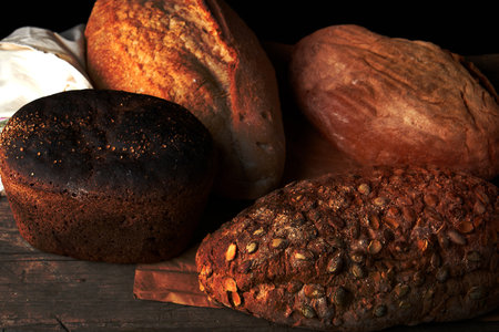 whole baked rye bread with pumpkin seeds and other types on a wooden table, top viewの写真素材