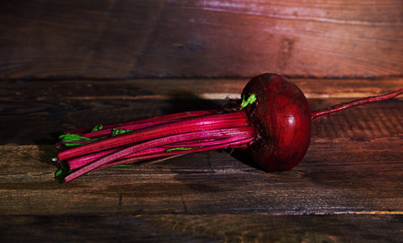 Whole raw red beet with tops on a brown wooden backgroundの写真素材