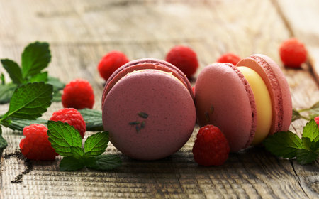 stack of baked raspberry macarons and berries on a gray wooden tableの写真素材