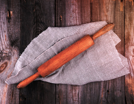 old brown wooden rolling pin on a gray linen napkin, top viewの写真素材