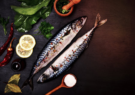 Two mackerel in spices for preparation on a black background, empty space on the rightの写真素材