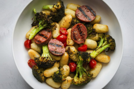 a bowl containing pan-fried gnocchi mixed with grilled sausage slicesの写真素材