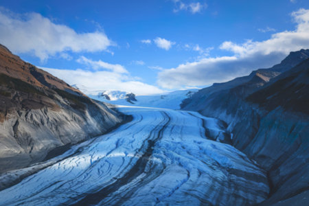 a glacier flowing between mountain slopes under a blue skyの写真素材