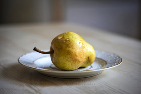 A photo of a ripe pear lying on a white plateの写真素材