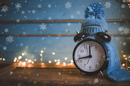 A photo of an alarm clock wearing a knitted hat and a knitted scarf