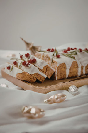 a cake with white icing and red berries on top of a wooden cutting boardの写真素材