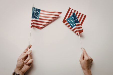 Two hands holding small American flags on a white background