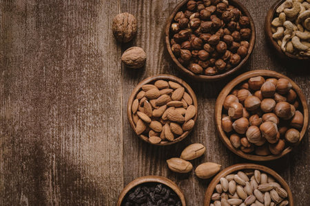 A collection of various nuts arranged in bowls on a wooden surface