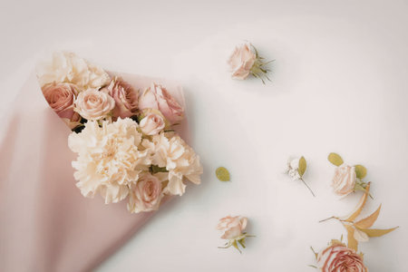 A stunning bouquet of pink and white roses wrapped in pink paper on a white background with scattered flower petals and buds.の写真素材
