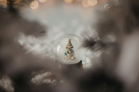 A small Christmas tree inside a snow globe with fog and lights in the background.