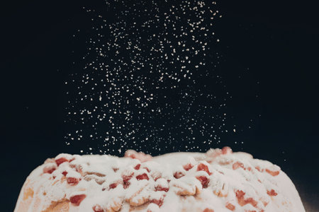 A close-up shot of a donut being sprinkled with cinnamon sugar against a dark background.