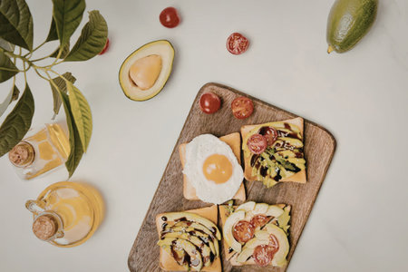 A wooden board with avocado toast and a fried egg on top, surrounded by fresh ingredients