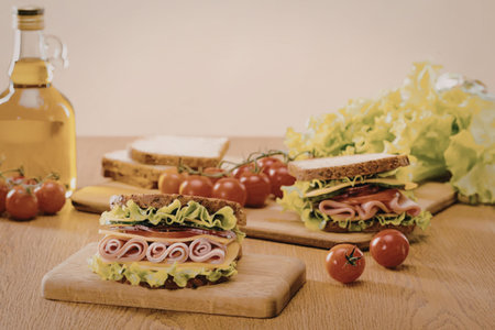 Two halves of sandwiches on wooden boards with tomatoes and lettuce