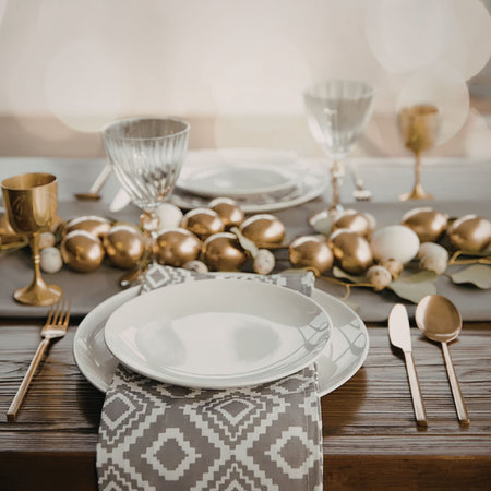 A beautifully set table with gold accents, white plates, and a decorative runner, perfect for a special occasion or holiday dinner.の写真素材