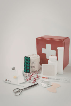 A first aid kit with various medical supplies including scissors, pills, bandages, and bottles