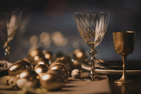 A beautifully arranged table setting featuring golden accents, wine glasses, and decorative eggs.