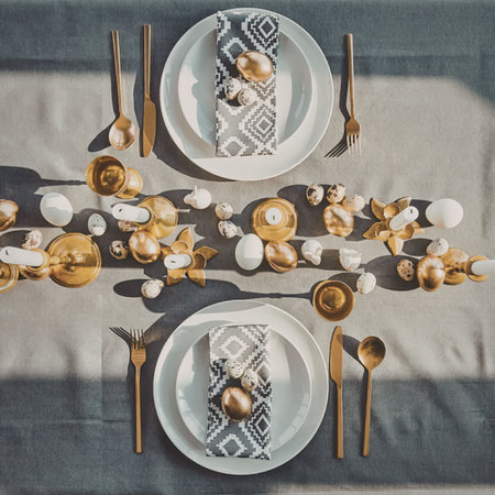 A beautifully set table with golden accents, white plates, and decorative napkins.