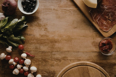 A wooden table with various food ingredients such as mushrooms, peppers, olives, and meat.の写真素材