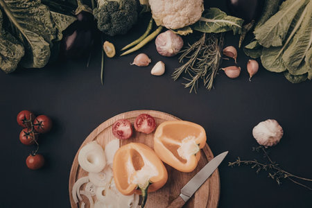 A cutting board with sliced vegetables and a knife on a dark backgroundの写真素材