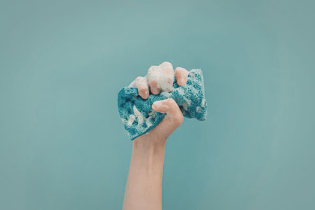A hand holding a blue and white cloth against a blue background