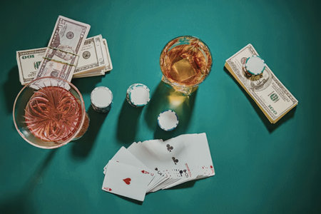 A collection of items commonly associated with gambling, including poker cards, money, and drinks,...