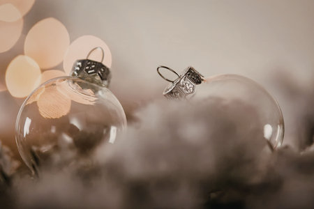 Close-up of clear glass Christmas ornaments on a fuzzy surface with blurred lights in the...