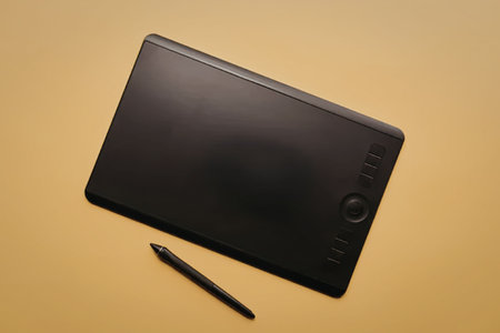 A graphic tablet and stylus pen on a yellow surface, likely used for digital art or design.の写真素材