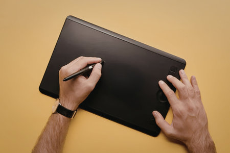 A person using a drawing tablet with a stylus on a yellow background