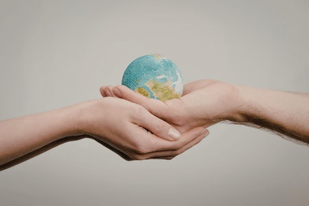 Two hands gently holding a small globe, symbolizing care and protection for the planet.の写真素材