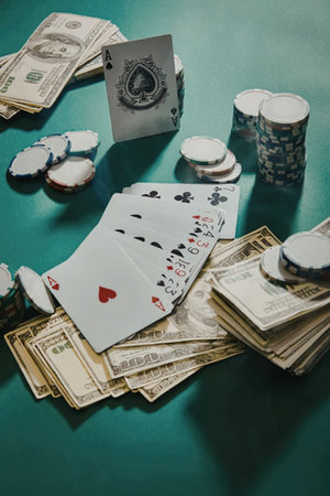 A poker game setup with playing cards, chips, and cash on a green table.