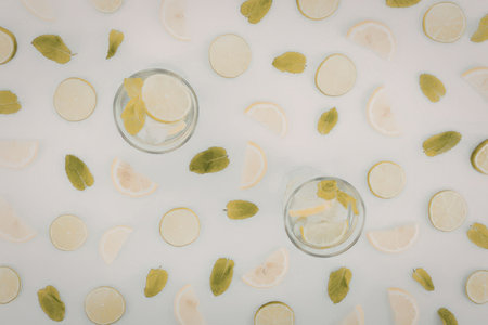 A visually appealing arrangement of mint leaves and glasses of infused water on a clean white background, perfect for a healthy beverage concept.の写真素材