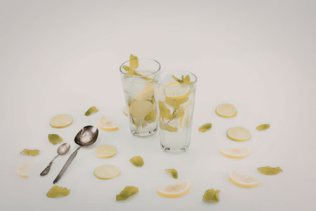 Two glasses of mojito with lime slices and mint leaves on a white background