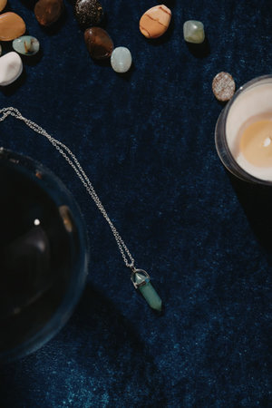 a serene arrangement of stones, jewelry, and a candle on a blue velvet surfaceの写真素材