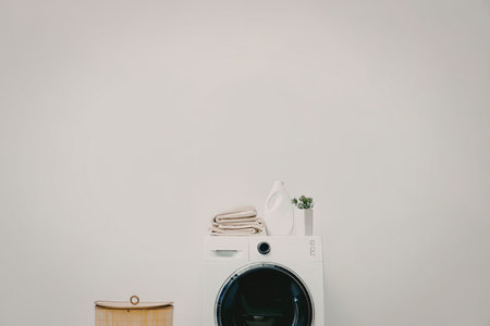 A washing machine with towels on top and a laundry basket beside it.