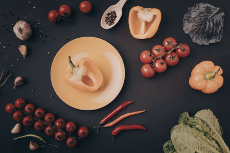 A vibrant arrangement of fresh vegetables and fruits on a plate and surrounding it on a black...