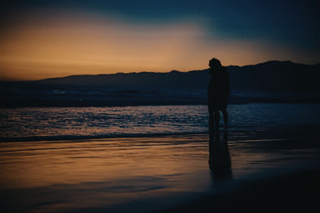 A person standing alone on the beach at sunsetの写真素材