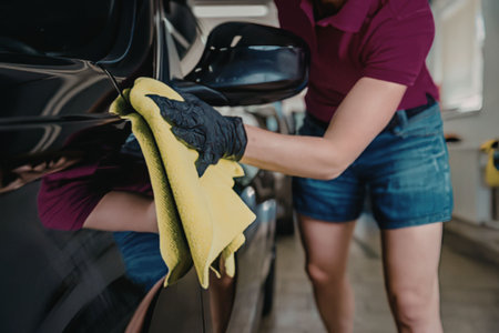 Woman cleaning car with yellow cloth